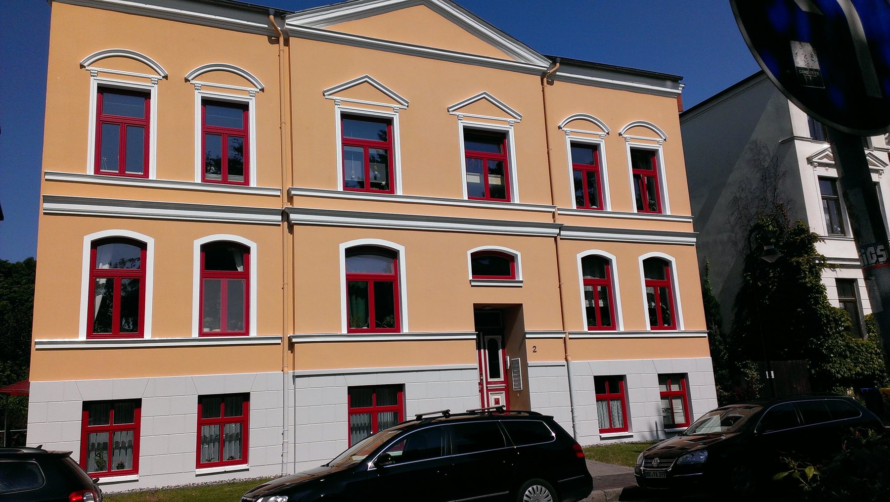 Fassade nach der Sanierung mit lackierten roten Fenstern