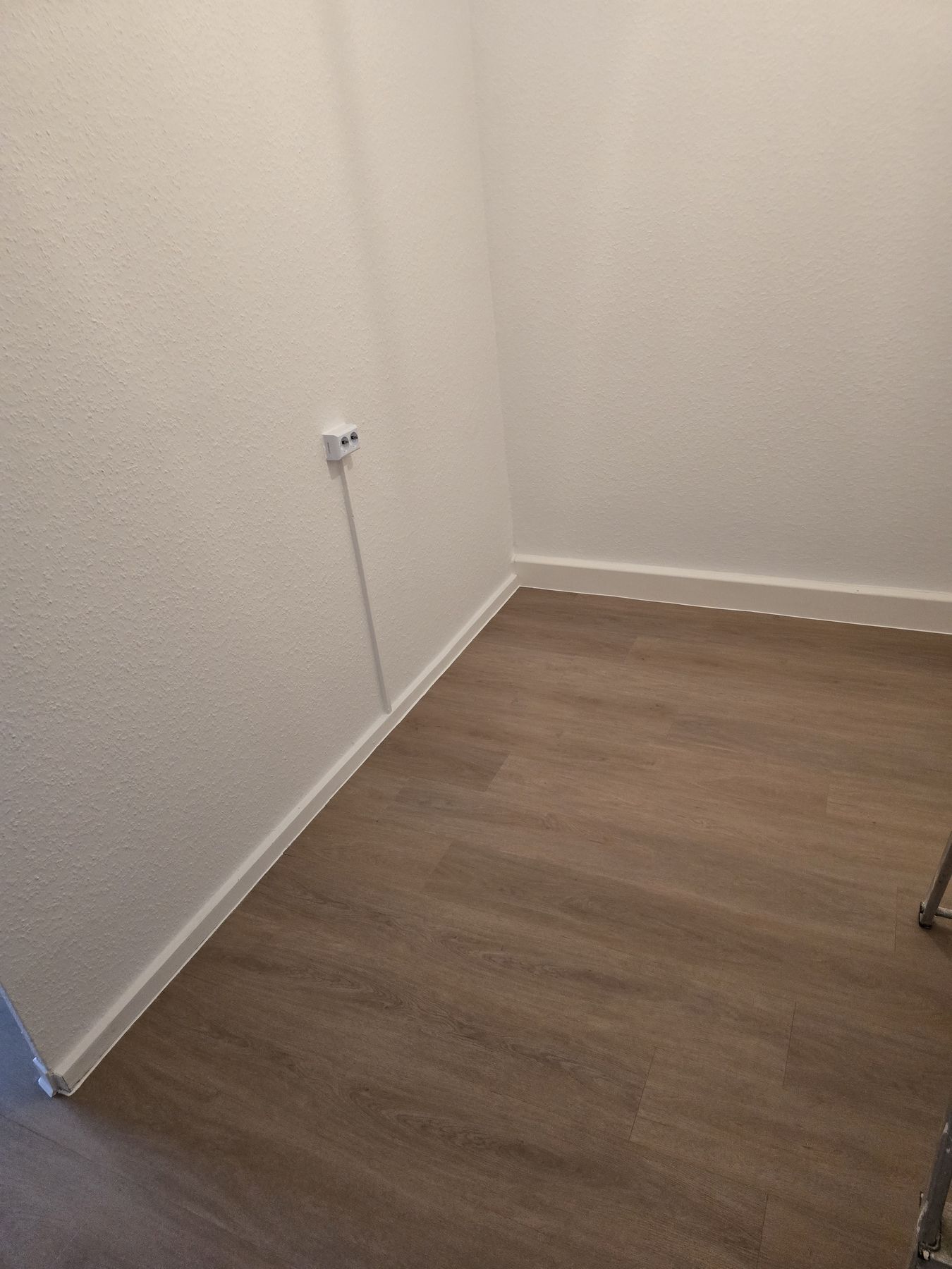Weiß gestrichene Wandflächen und verlegter Bodenbelag